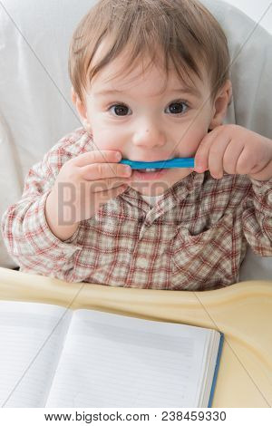 Little baby boy is playing with pen and note book