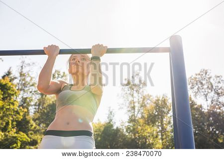 Fit Woman Doing Pull-ups. Young Athletic Fitness Woman Working Out At Outdoor Gym Doing Pull Ups At 