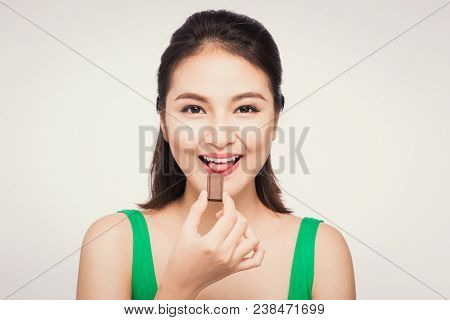 Portrait Of A Young Asian Woman Holding A Chocolate Bar To Enjoy The Taste