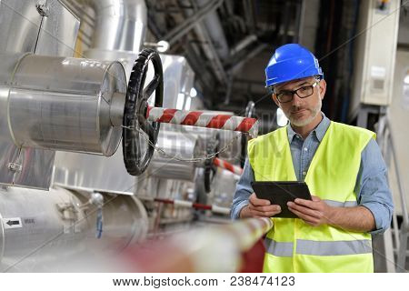 Industrial technician connected with tablet in recyling plant