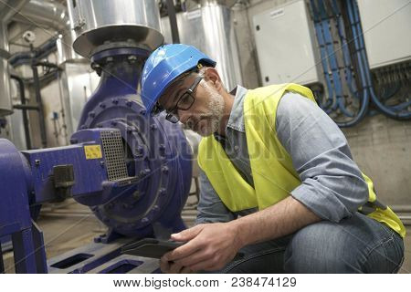 Industrial technician connected with tablet in recyling plant