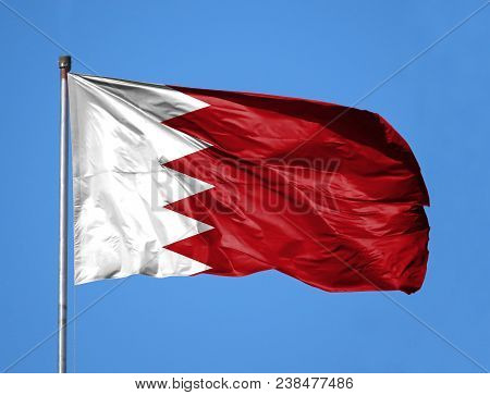 National Flag Of Bahrain On A Flagpole In Front Of Blue Sky.