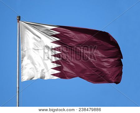 National Flag Of Qatar On A Flagpole In Front Of Blue Sky.