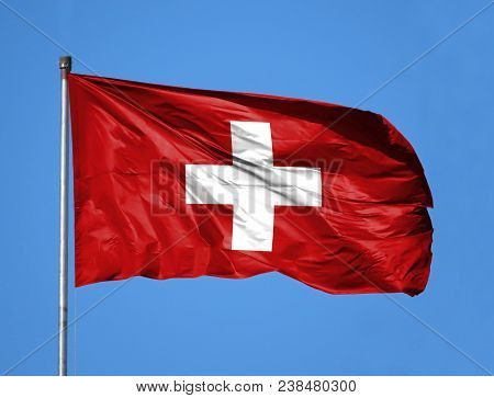 National Flag Of Switzerland On A Flagpole In Front Of Blue Sky.