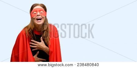 Middle age super hero woman wearing red mask and cape confident and happy with a big natural smile laughing isolated blue background