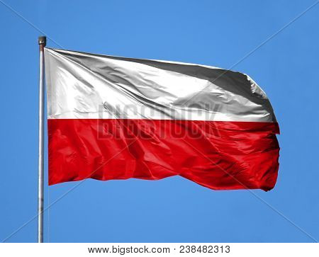 National Flag Of Poland On A Flagpole In Front Of Blue Sky.