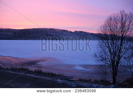 View From The Window On Ice Covered Lake And Mountain Ahead In Evening
