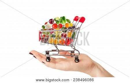 Female Hand Holding Grocery Cart With Vegetables And Fruits Falling In It Isolated On White. Healthy