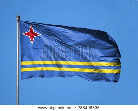 National Flag Of Aruba On A Flagpole In Front Of Blue Sky.