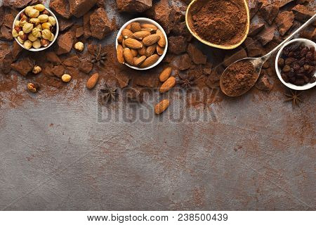 Dark Broken Chocolate Pieces On Dark Background, Cocoa Powder And Various Nuts In Bowls Closeup. Swe