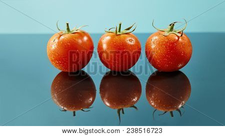 shot of red tomatoes surface with water drops isolated on glossy blue background