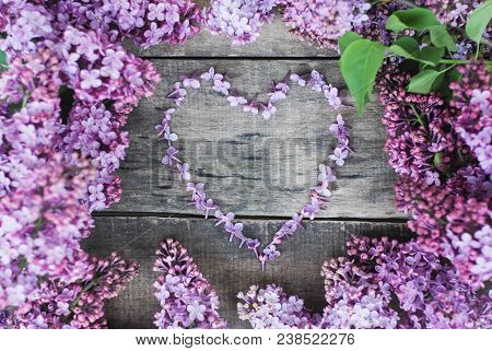 Spring Flowers. Lilac Flowers Frame Heart Shape Textured Rustic Gray Wooden Background.