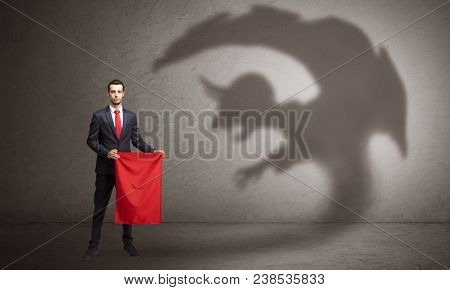Businessman standing with red cloth in his hand and imp shadow on the background
