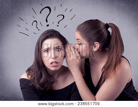 A teenager girl looking confused with drawn question marks above the head, while a girlfriend whispers something in her ear concept.