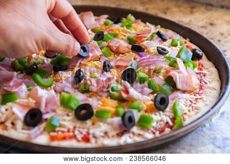 Making Pizza. Cook's Hand Sprinkles Olives. American Style, Cooking In A Baking Dish