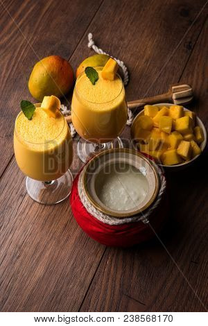 Mango Lassi Or Smoothie In Big Glass Or Small Bottles With Curd, Cut Fruit Pieces And Blender. Moody