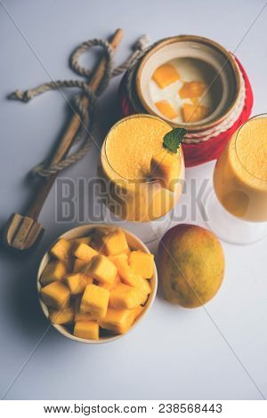 Mango Lassi Or Smoothie In Big Glass Or Small Bottles With Curd, Cut Fruit Pieces And Blender. Moody
