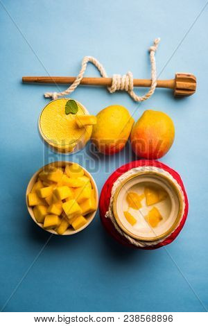 Mango Lassi Or Smoothie In Big Glass Or Small Bottles With Curd, Cut Fruit Pieces And Blender. Moody