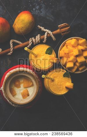 Mango Lassi Or Smoothie In Big Glass Or Small Bottles With Curd, Cut Fruit Pieces And Blender. Moody