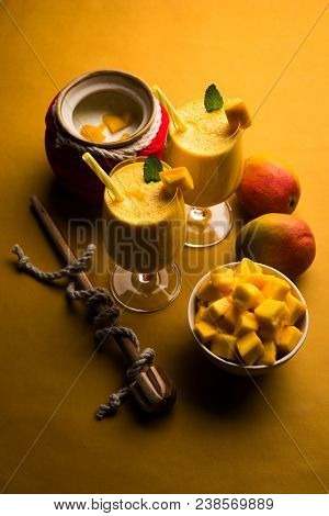 Mango Lassi Or Smoothie In Big Glass Or Small Bottles With Curd, Cut Fruit Pieces And Blender. Moody