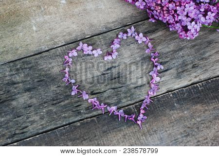 Spring Flowers. Lilac Flowers Frame Heart Shape Textured Rustic Gray Wooden Background.