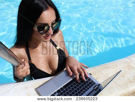 Sexy Girl In A Black Bikini Uses A Laptop With A Black Screen In The Pool. Work On Vacation. Glamoro
