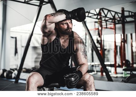 Tired Male Boxer Sitting On Stool In Gym