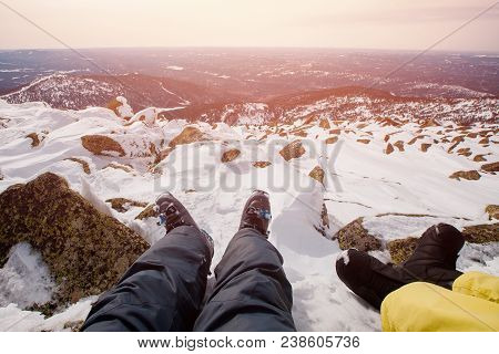 Legs In Ski And Snowboard Boot On Background Of Snow And Mountains