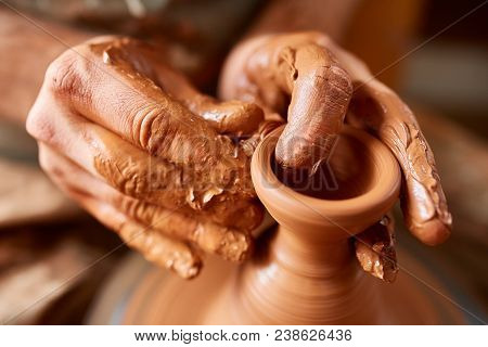 Close-up Hands Of A Male Potter In Plaid Shirt And Dirty Apron Who Molds A Vase From Clay, Selective