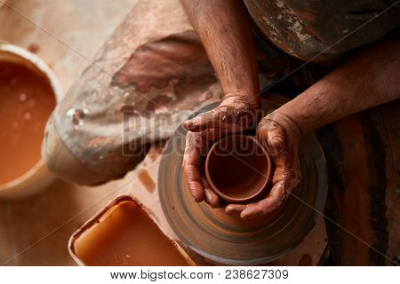 Close-up Hands Of A Male Potter In Plaid Shirt And Dirty Apron Who Molds Bowl From Clay, Selective F