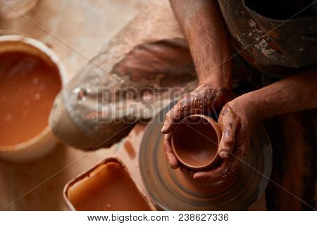 Close-up Hands Of A Male Potter In Plaid Shirt And Dirty Apron Who Molds Bowl From Clay, Selective F