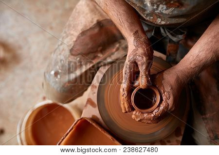 Close-up Hands Of A Male Potter In Plaid Shirt And Dirty Apron Who Molds Bowl From Clay, Selective F