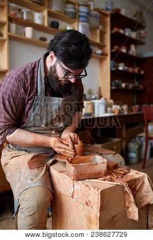 Portrait Of A Handsome Bearded Male Potter In Plaid Shirt And Dirty Apron Who Molds Bowl From Clay, 