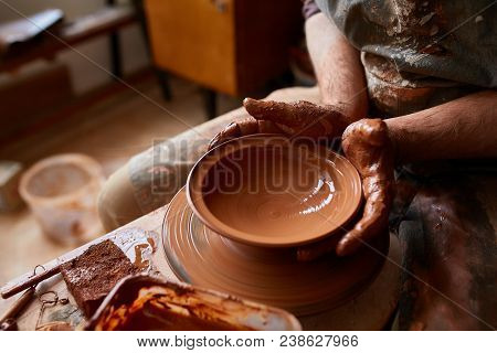 Close-up Hands Of A Male Potter In Plaid Shirt And Dirty Apron Who Molds Bowl From Clay, Selective F