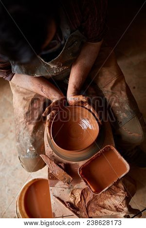Close-up Hands Of A Male Potter In Plaid Shirt And Dirty Apron Who Molds Bowl From Clay, Selective F