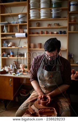 Portrait Of A Handsome Bearded Male Potter In Plaid Shirt And Dirty Apron Who Molds Bowl From Clay, 