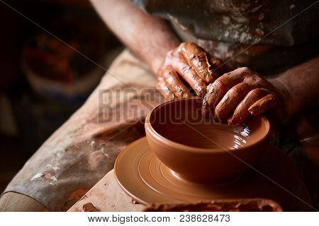 Close-up Hands Of A Male Potter In Plaid Shirt And Dirty Apron Who Molds Bowl From Clay, Selective F