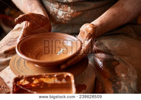 Close-up Hands Of A Male Potter In Plaid Shirt And Dirty Apron Who Molds Bowl From Clay, Selective F