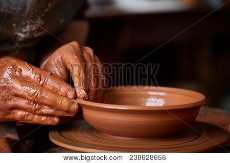 Close-up Hands Of A Male Potter In Plaid Shirt And Dirty Apron Who Molds Bowl From Clay, Selective F