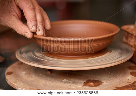 Close-up Hands Of A Male Potter In Plaid Shirt And Dirty Apron Who Molds Bowl From Clay, Selective F