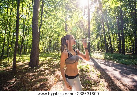 Young Woman Drinking Water After Running Outdoors.