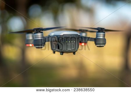 A Dji Spark Drone In Color Alpine White Mid-air Flying In A Forrest With The Trees In The Background
