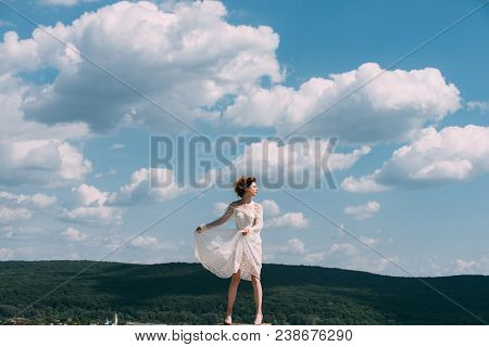 Girl On Sunny Blue Sky Background In Summer. Girl In White Summer Dress Pose On Blue Sky Abckground