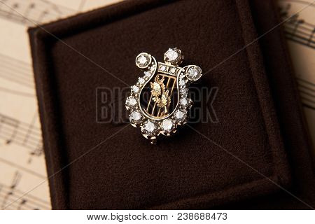 Gold Brooch With Diamonds In The Form Of A Harp. Luxury Female Jewellery, Close-up. Selective Focus