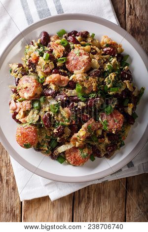 Brazilian Beans With Greens, Sausages, Bacon And Eggs Close-up On A Plate. Vertical Top View