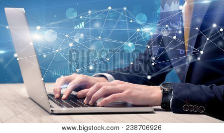 Businessman typing on laptop with linked reports charts grapghs around