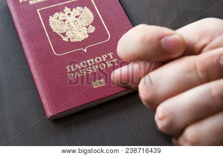 Men's Hand Shows The Fico On Red Passport Backgound. Symbol Of Sanctions. Negative Concept. Closeup