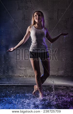 Girl In The White Shirt With Water Drop In A Dark Room Illuminated By Light During A Photoshoot With