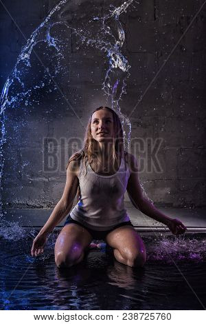 Girl In The White Shirt With Water Drop In A Dark Room Illuminated By Light During A Photoshoot With