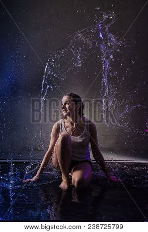 Girl In The White Shirt With Water Drop In A Dark Room Illuminated By Light During A Photoshoot With